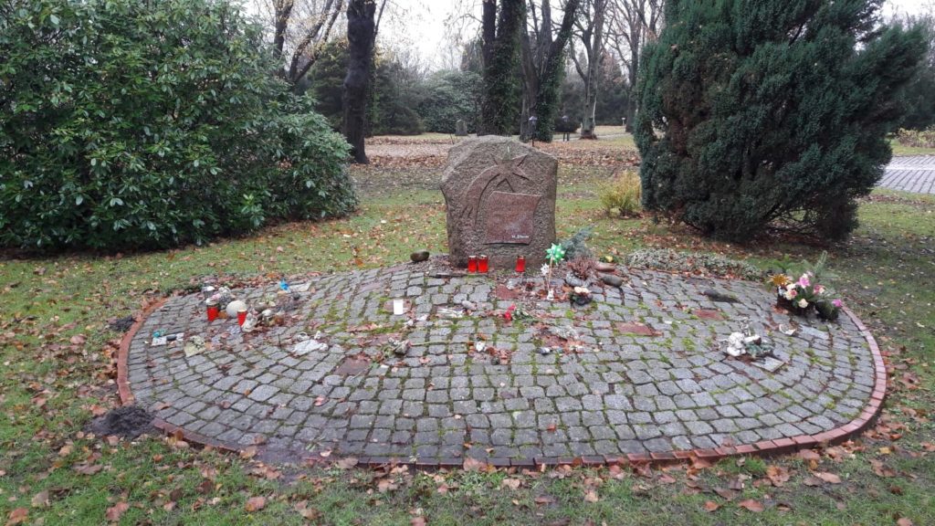 Ein Grabstein mit einer großen Ablagefläche davor. Auf dem Grabstein ist eine Sternschnuppe.