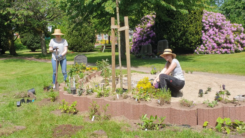 F Ö J lerin auf dem Friedhof, pflanzt Blumen ein.