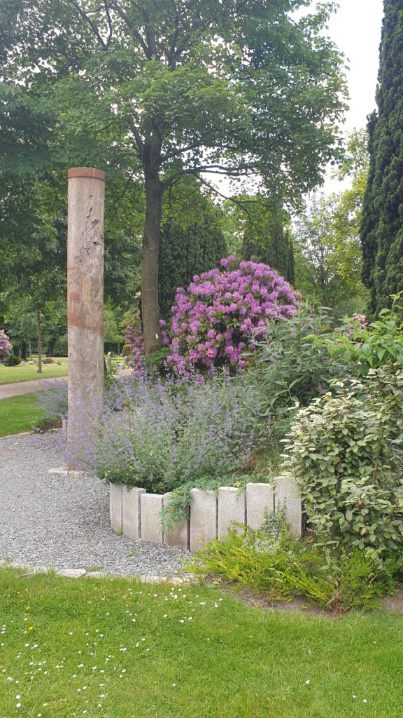 Blumen und eine Stele auf dem Friedhof.