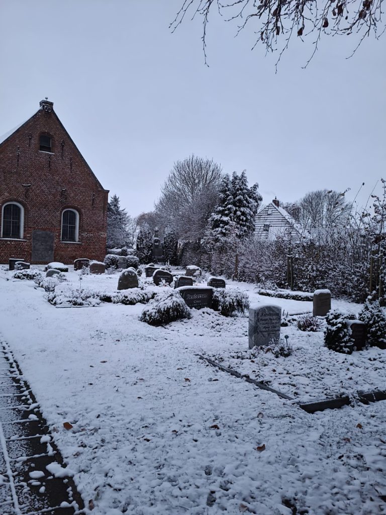 Grabmale mit leichtem Schnee bedeckt, im Hintergrund ist die Osterkapelle zu sehen.