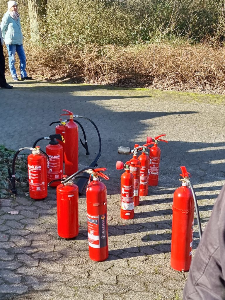 Verschiedene Feuerlöscher stehen auf dem Boden.