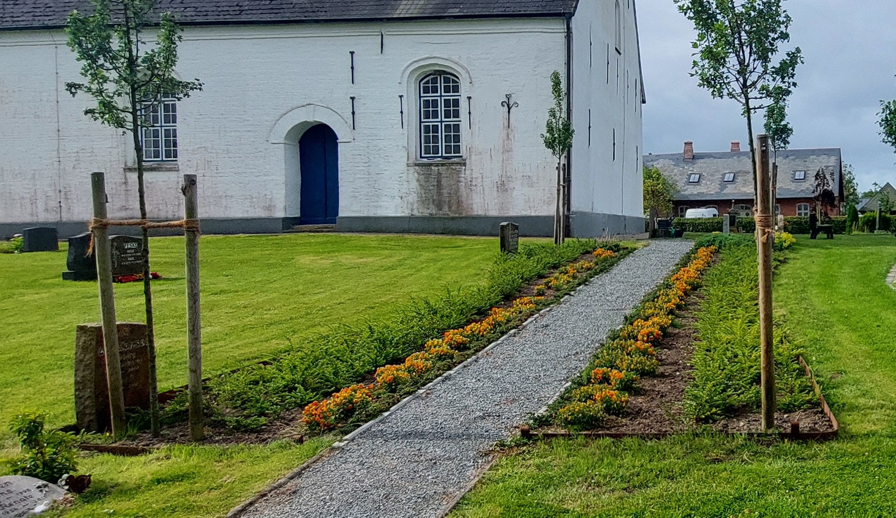 Ein Weg, rechts und links davon bepflanzte Grabflächen